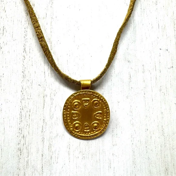 Mayan design gold tone pendant purchased in Costa Rica, on golden suede cord